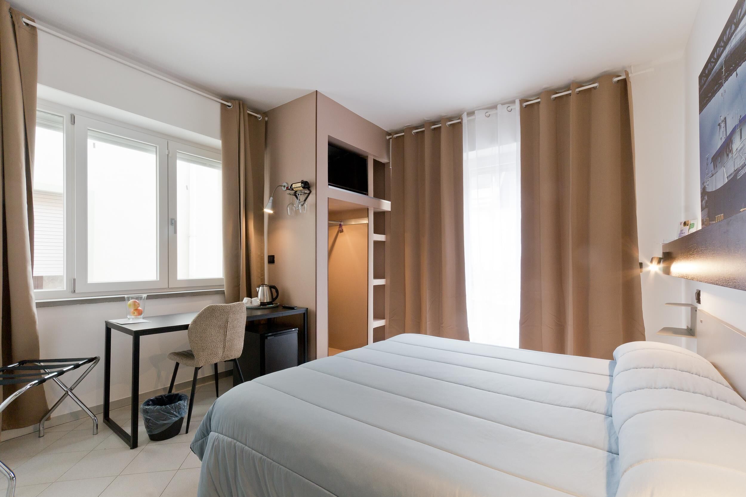 Une chambre d’hôtel équipée d’un lit, d’un bureau, d’une chaise et d’une petite kitchenette.