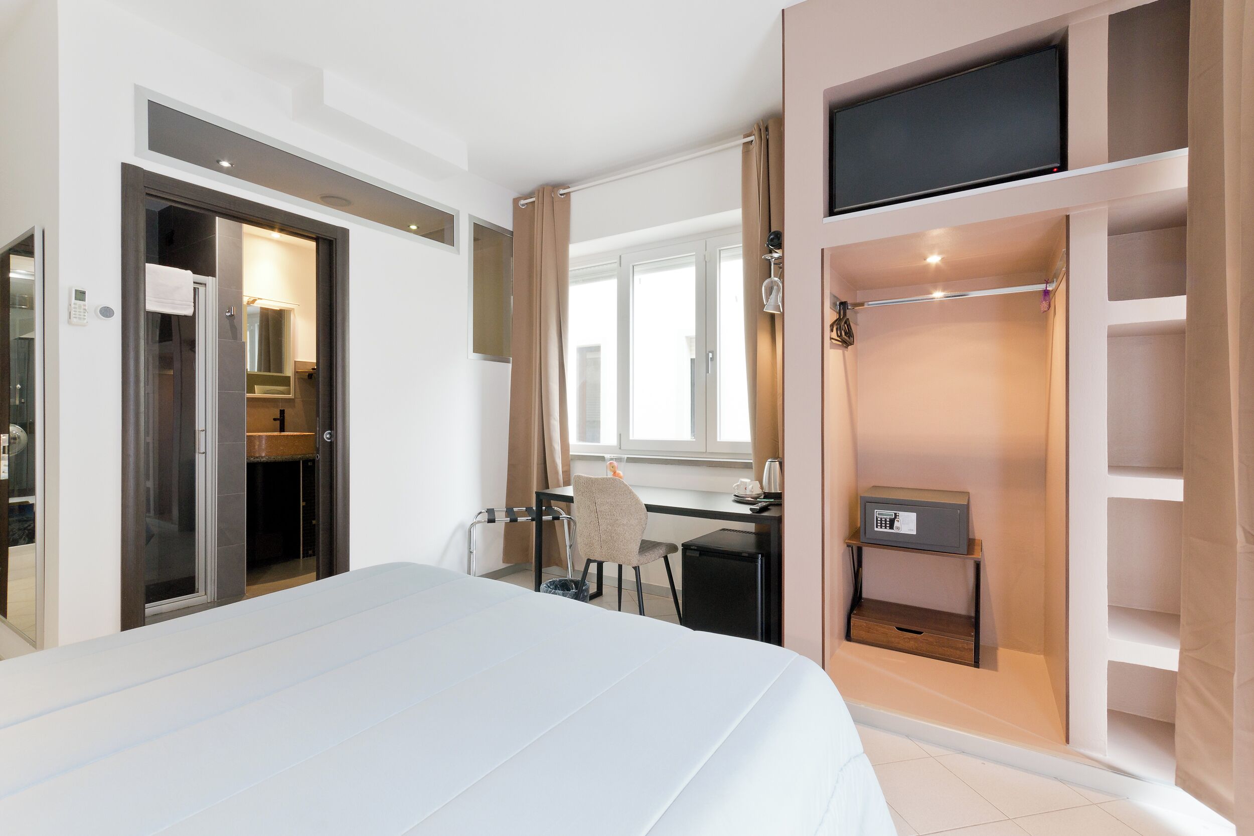 Une chambre d’hôtel équipée d’un lit, d’un bureau, d’une chaise, d’une télévision et d’un espace douche.