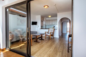 Et moderne interiør med spiseplads, køkken og en glasdør, der fører ud til en balkon.
