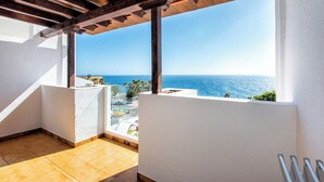 A balcony with a view of the sea, wooden beams, white walls, and a tiled floor. - Apartamentos Albatros (Adeje)