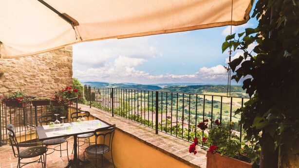 Una terraza con mesa y sillas, vista al campo y un muro de piedra.