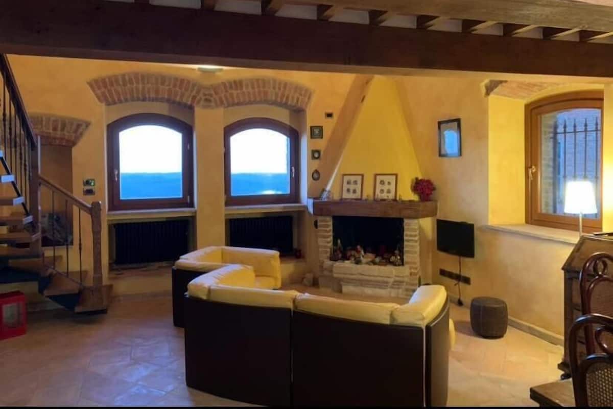 Un salón con chimenea, un sofá y vistas al mar a través de ventanales arqueados.