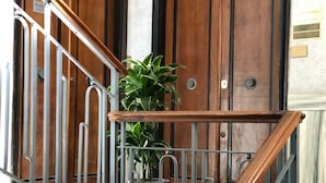 A staircase with metal railings and wooden steps, leading to a room with a wooden door and a potted plant. - Aventino Guest House (Rome)
