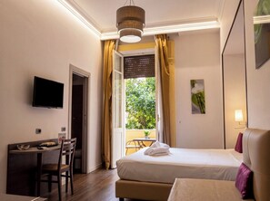 A hotel room with a bed, a desk with a chair, a television, and a window with curtains. - GHR Aventino Inn  (Rome)