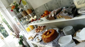 A breakfast buffet with various food items, including pastries, fruits, and a cake. - Aventino Guest House (Rome)