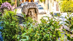 A statue in a garden with a building in the background. - Aventino Guest House (Rome)