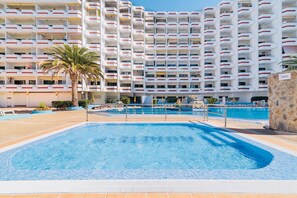 A hotel with multiple balconies, a swimming pool, and a palm tree. - HV Agaete Parque (San Bartolomé de Tirajana)