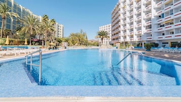 A swimming pool surrounded by palm trees and hotel buildings.