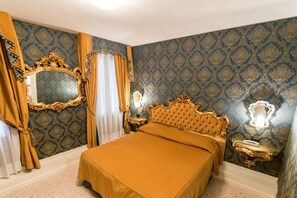 A bedroom with a large bed, ornate gold headboard, and a mirror with a gold frame. - Dimora Marciana (Venice)