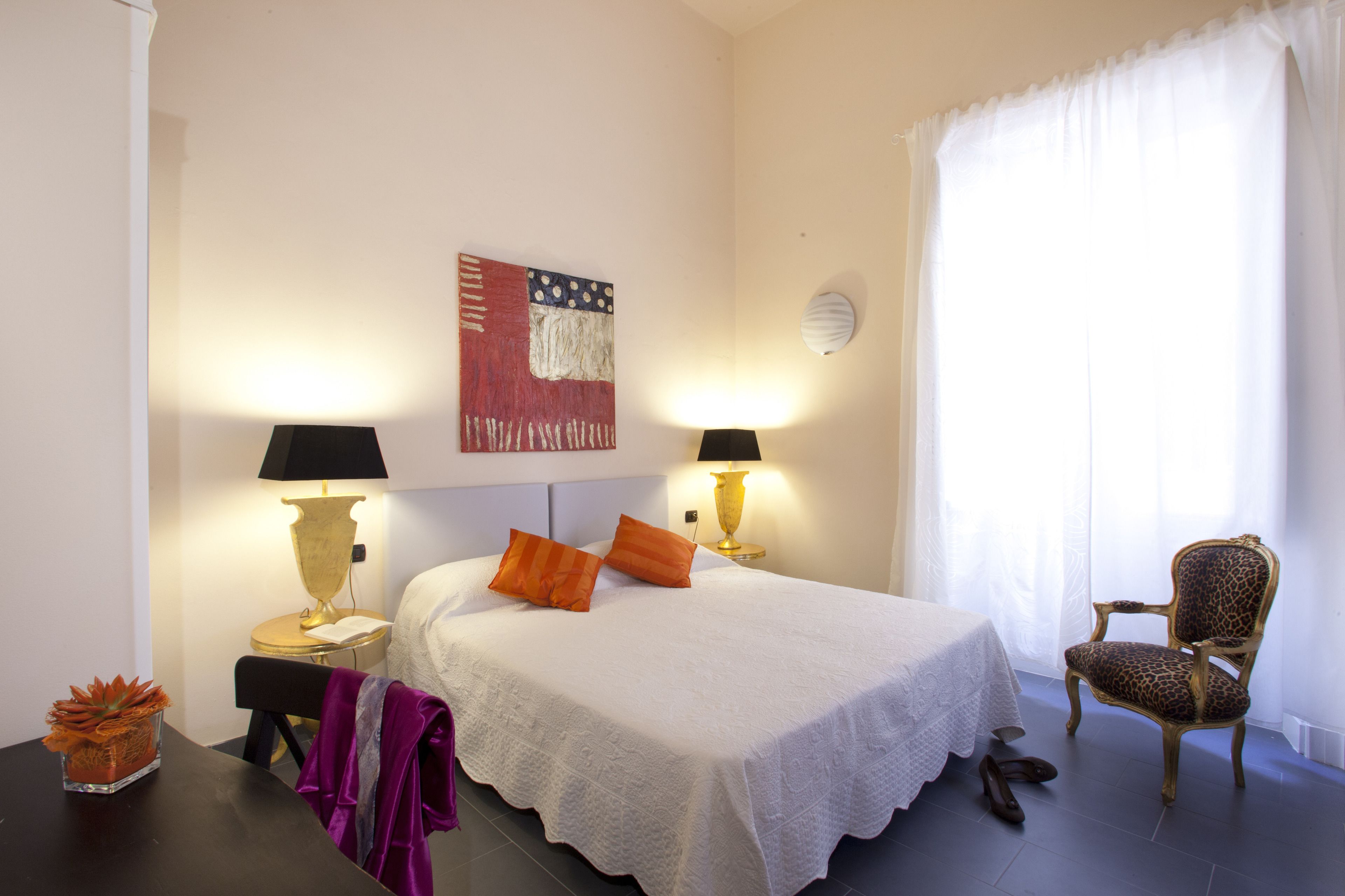 Ein Hotelzimmer mit einem Bett, zwei Nachttischlampen, einem Sessel mit Leopardenmuster und einem Wanddekor.