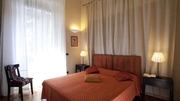 A hotel room with a large bed, a chair, two bedside tables with lamps, and a framed picture on the wall.