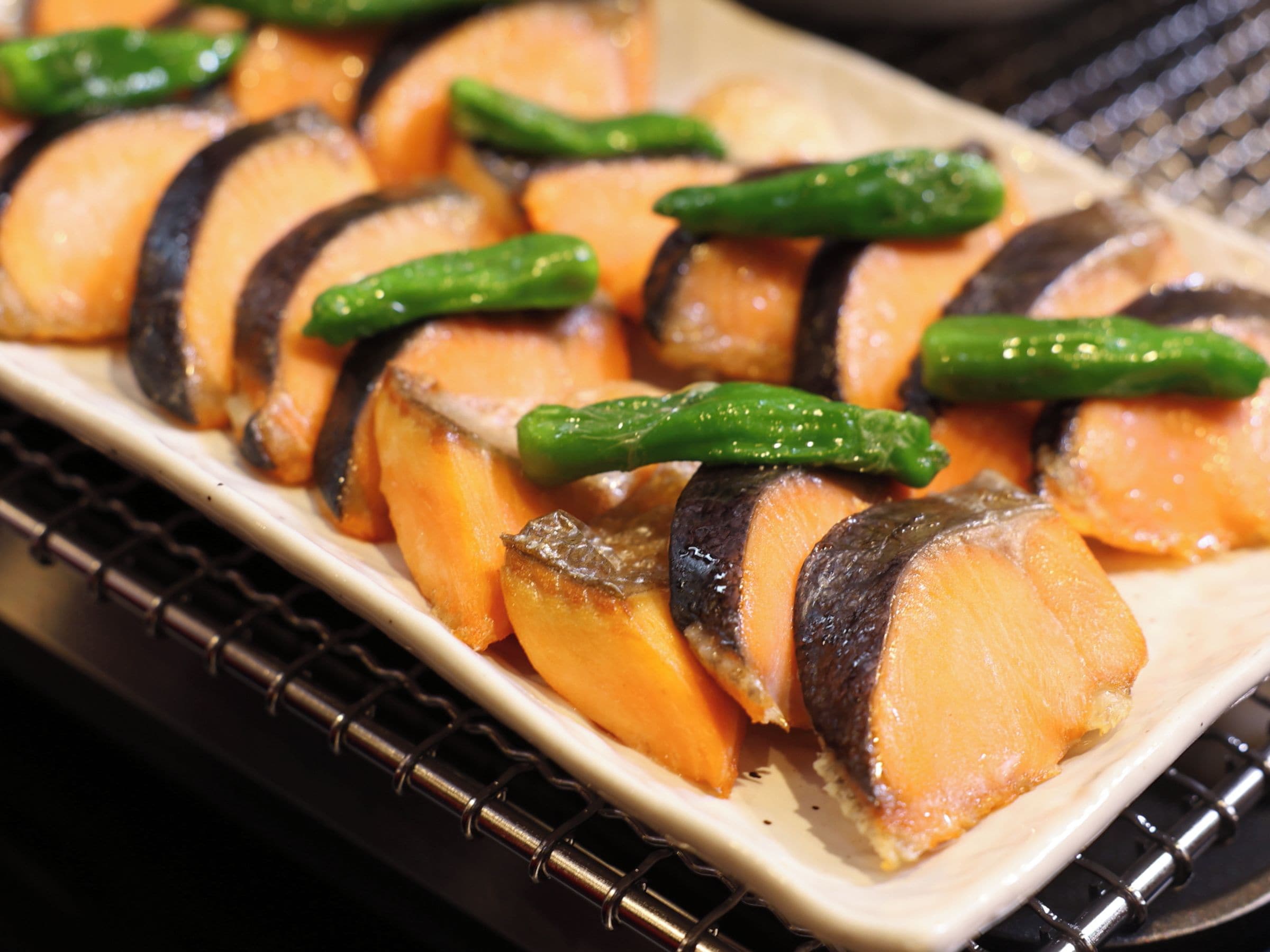 A tray of sliced sweet potatoes with green chili peppers.
