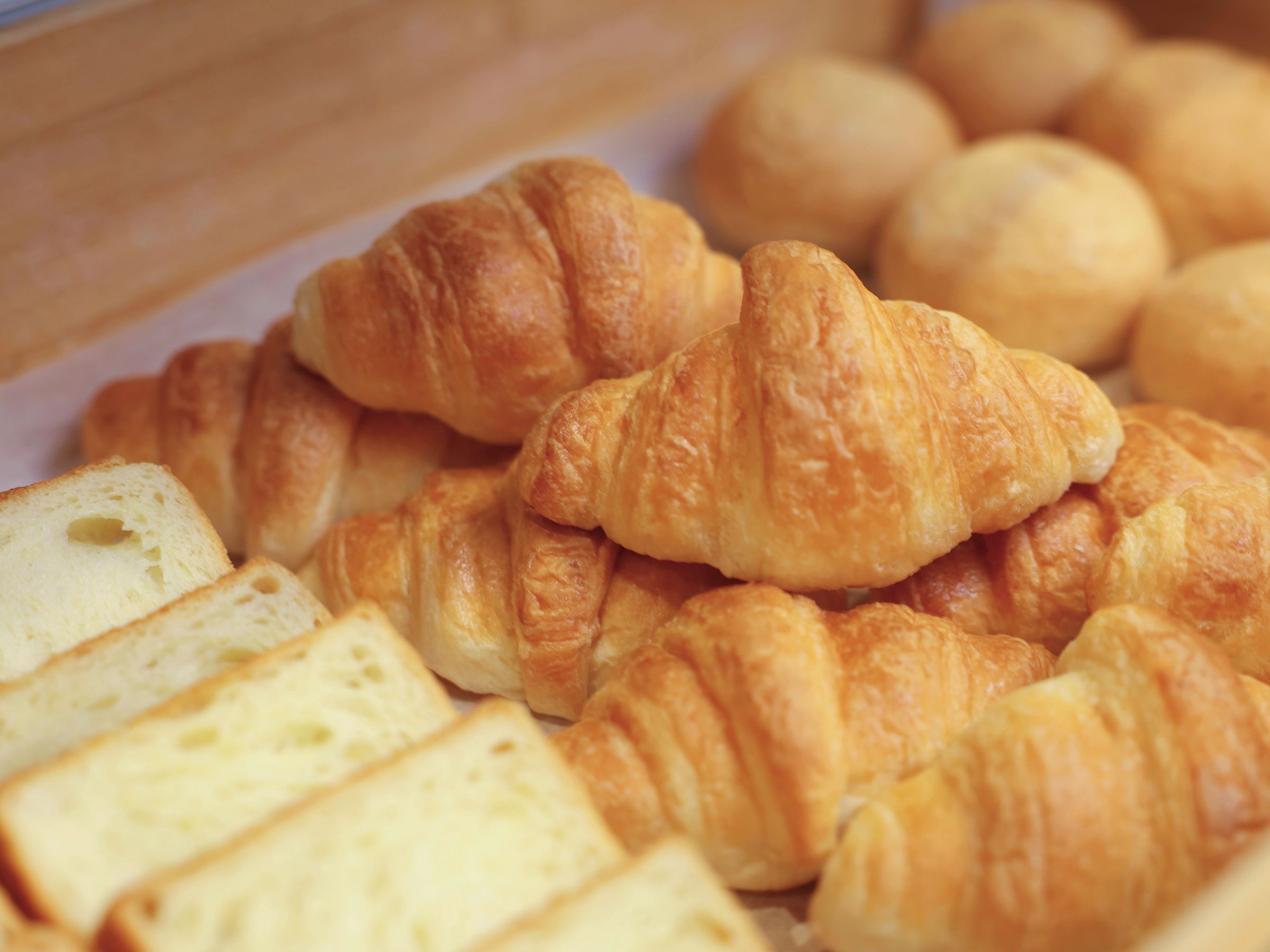 A display of various baked goods, including croissants and bread slices.