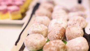 A tray of round pastries dusted with powdered sugar, arranged on a green leaf.