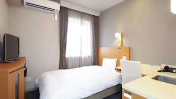 A hotel room with a bed, a desk with a chair, a television, a sink, and an air conditioning unit.