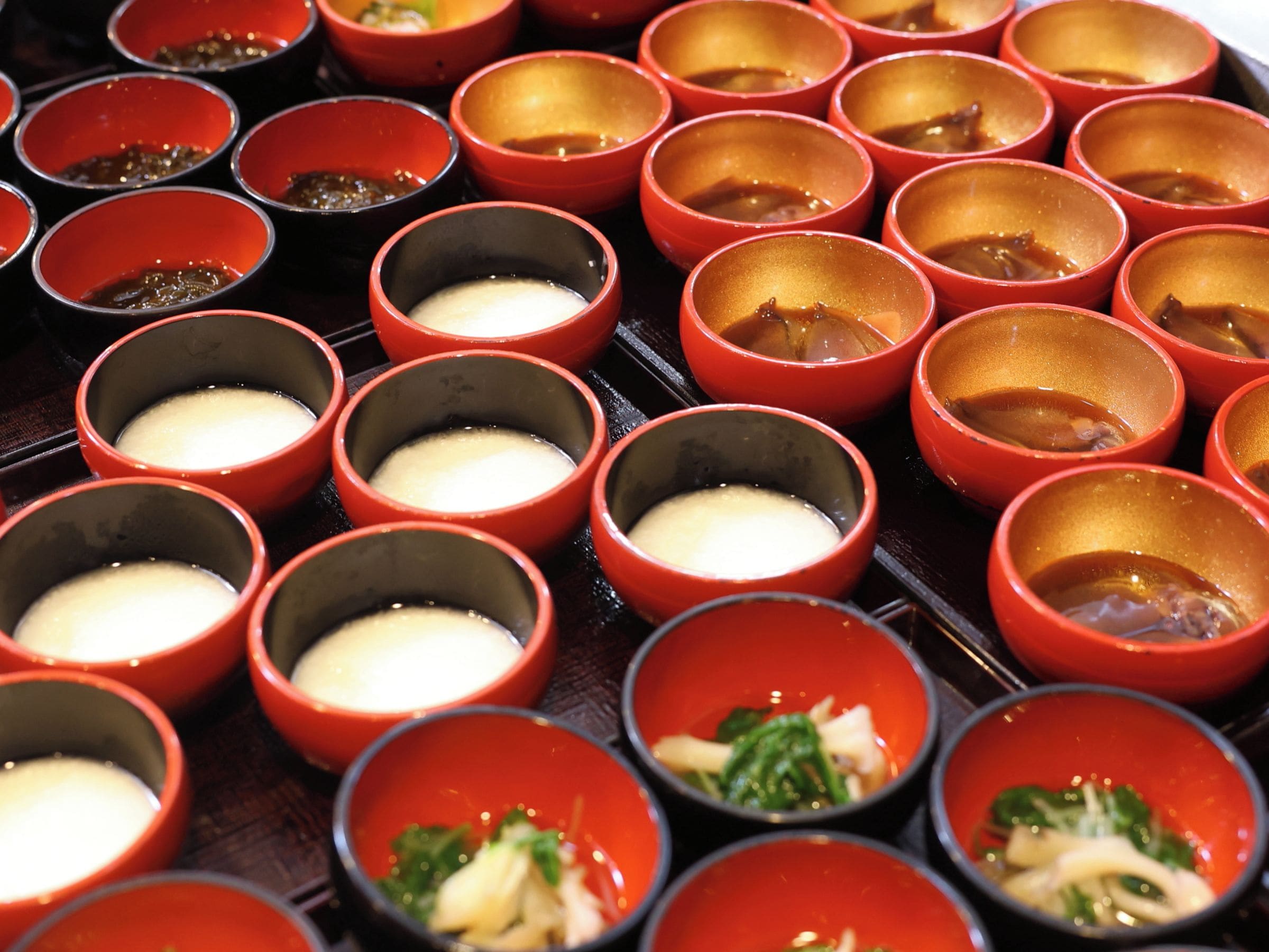 A variety of bowls with different contents, some with a creamy substance and others with vegetables.