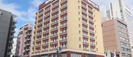 Un edificio de varios pisos con un letrero llamativo que dice 'dormy inn'.