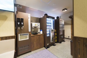 A hotel lobby with a coffee machine, a beverage dispenser, and a refrigerator with a beverage display. - Dormy Inn Toyama Natural Hot Spring (Toyama)