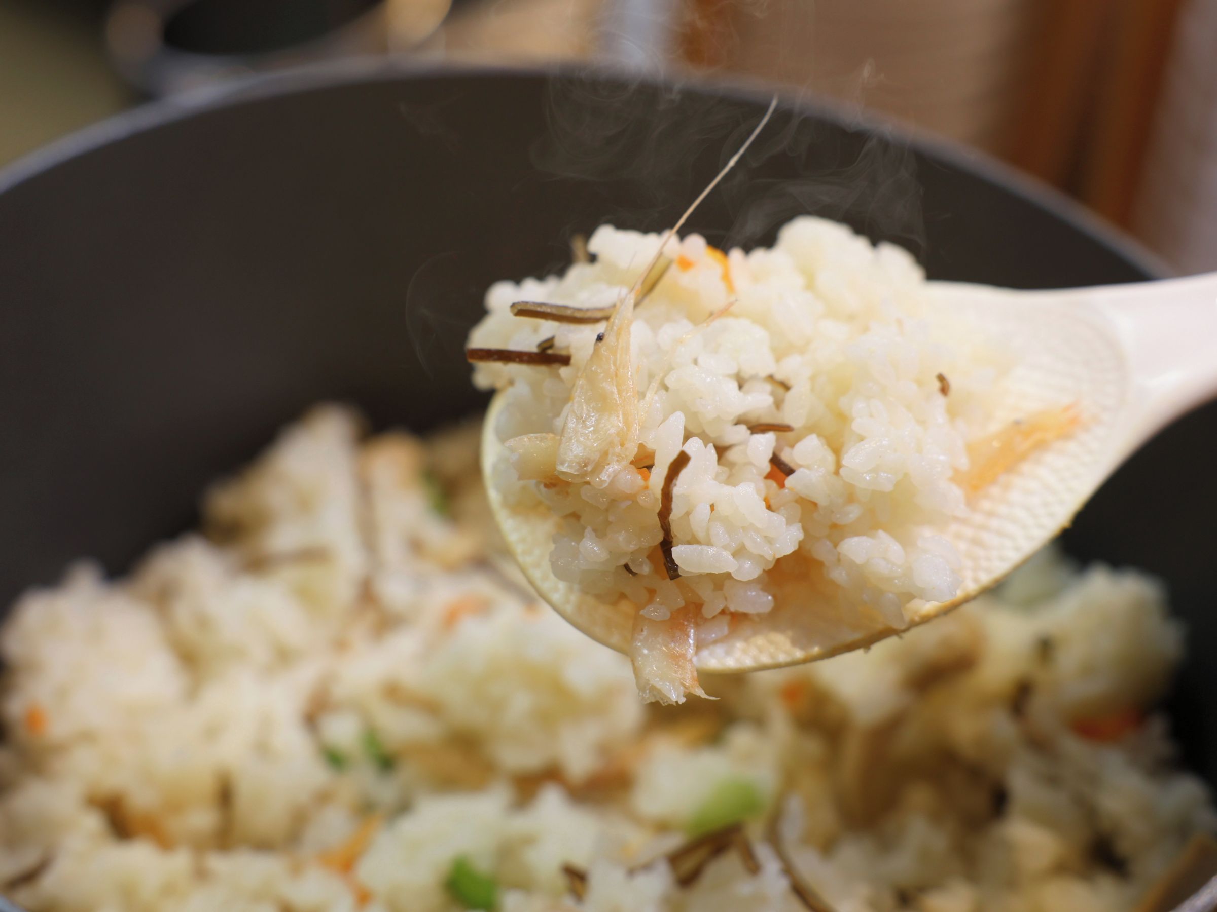 A close-up of a spoonful of rice with vegetables, indicating a meal being served.
