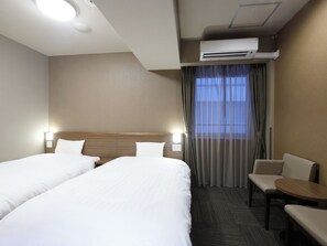 A hotel room with two beds, a desk, a chair, an air conditioning unit, and a window with curtains. - Dormy Inn Toyama Natural Hot Spring (Toyama)