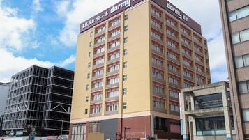 A multi-story building with a 'dormy inn' sign, featuring a modern architectural design with a flat roof and a mix of window styles.