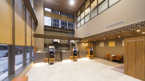 A modern lobby with a reception desk, seating area, and self-service kiosks. - Dormy Inn Toyama Natural Hot Spring (Toyama)