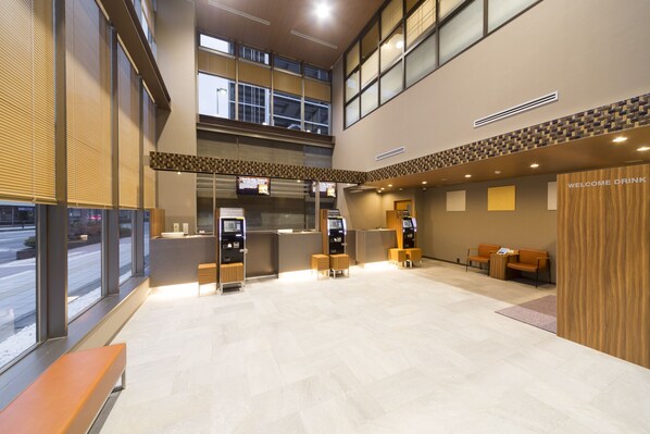 A modern lobby with a reception desk, seating area, and self-service kiosks. - Dormy Inn Toyama Natural Hot Spring (Toyama)