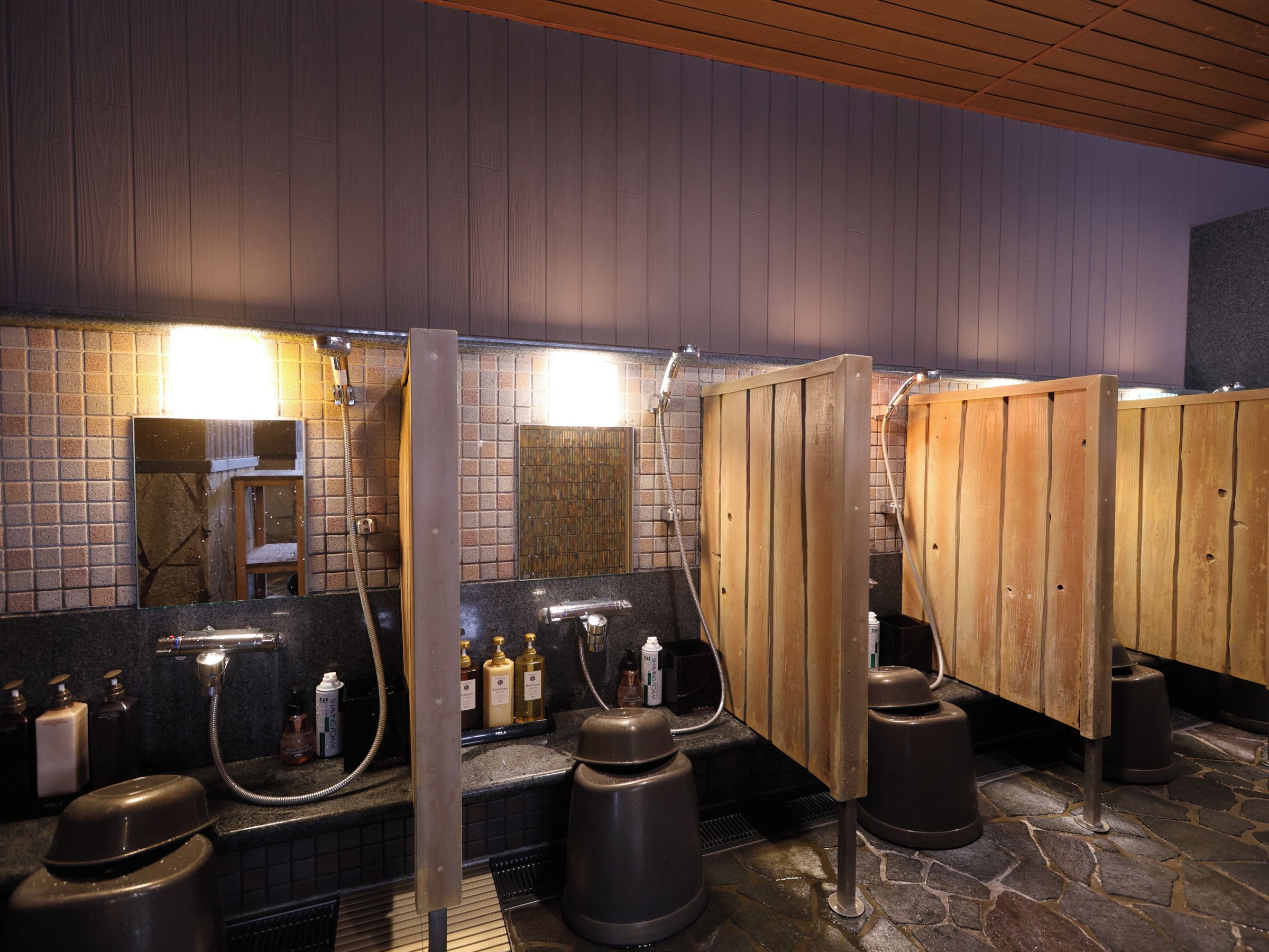 A public sauna with wooden benches, a tiled wall, and a mirror.
