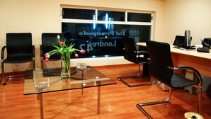 A modern office with a glass table, black chairs, a vase with flowers, and a computer on a desk. - Hotel Del Principado (Mexico City)