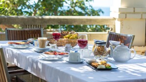 A table set for breakfast with various food items and drinks, overlooking a scenic view.