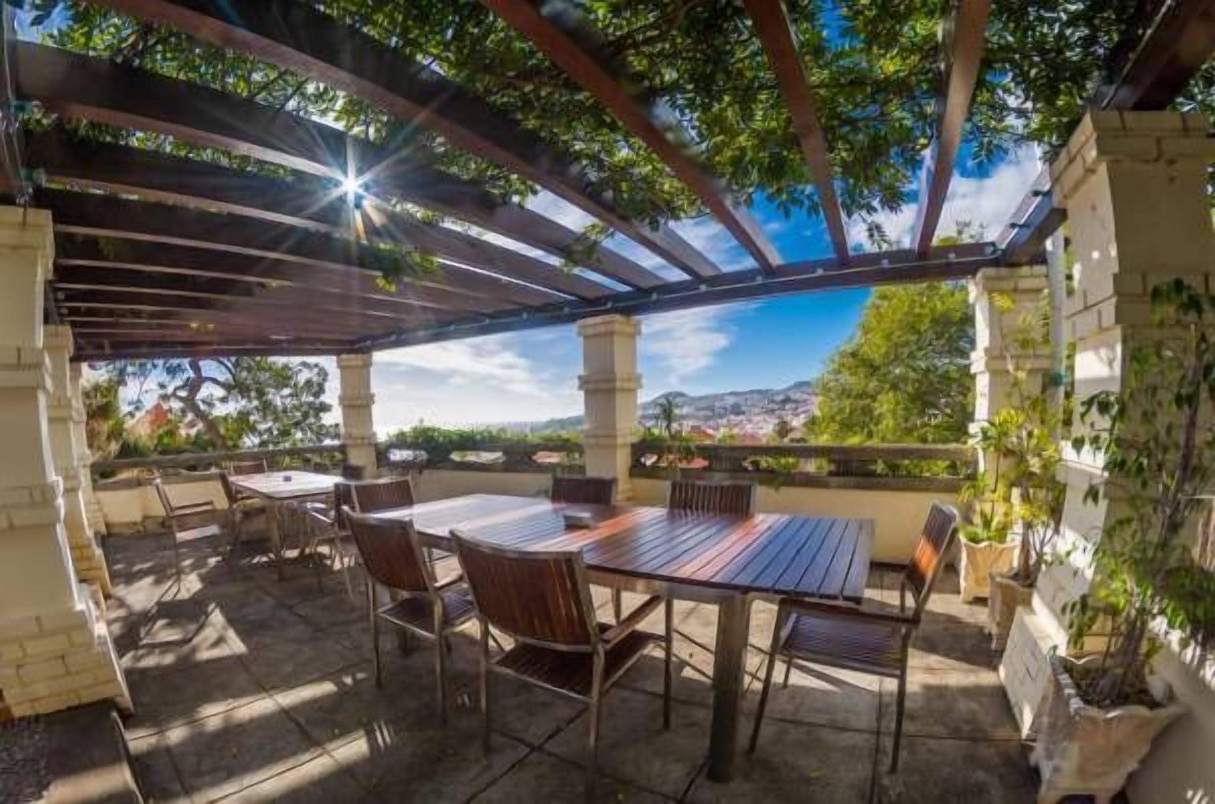 An outdoor patio with a pergola, tables, and chairs.