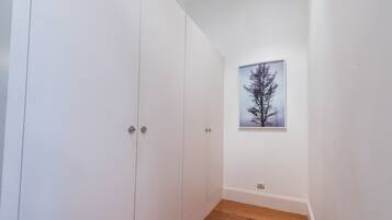 A room with white walls, a wooden floor, and a framed picture of a tree.