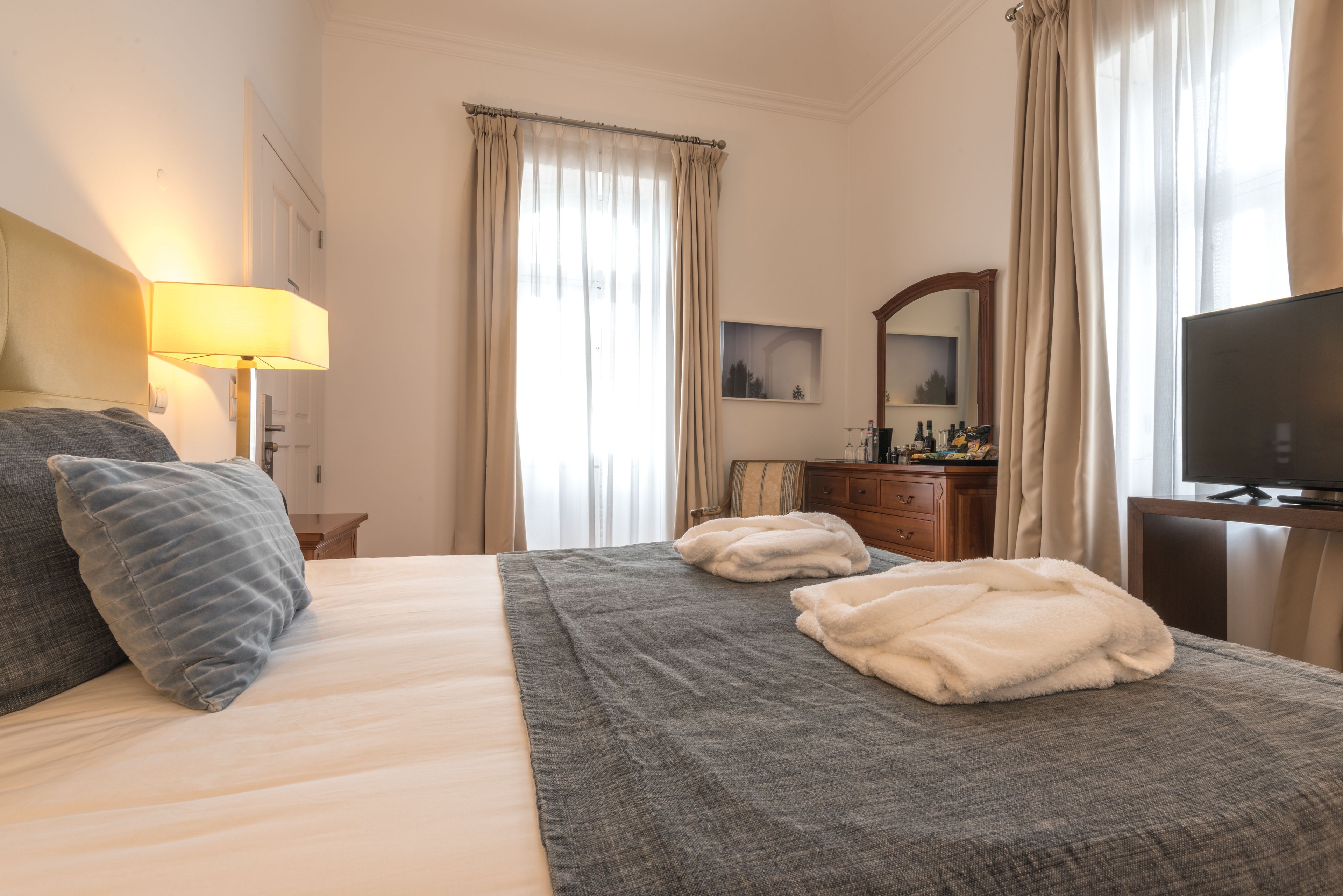 Een hotelkamer met een bed, een bureau, een televisie en een lamp.