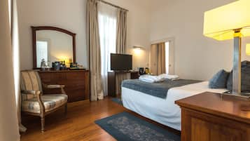 A hotel room with a bed, a desk, a chair, a television, and a lamp.