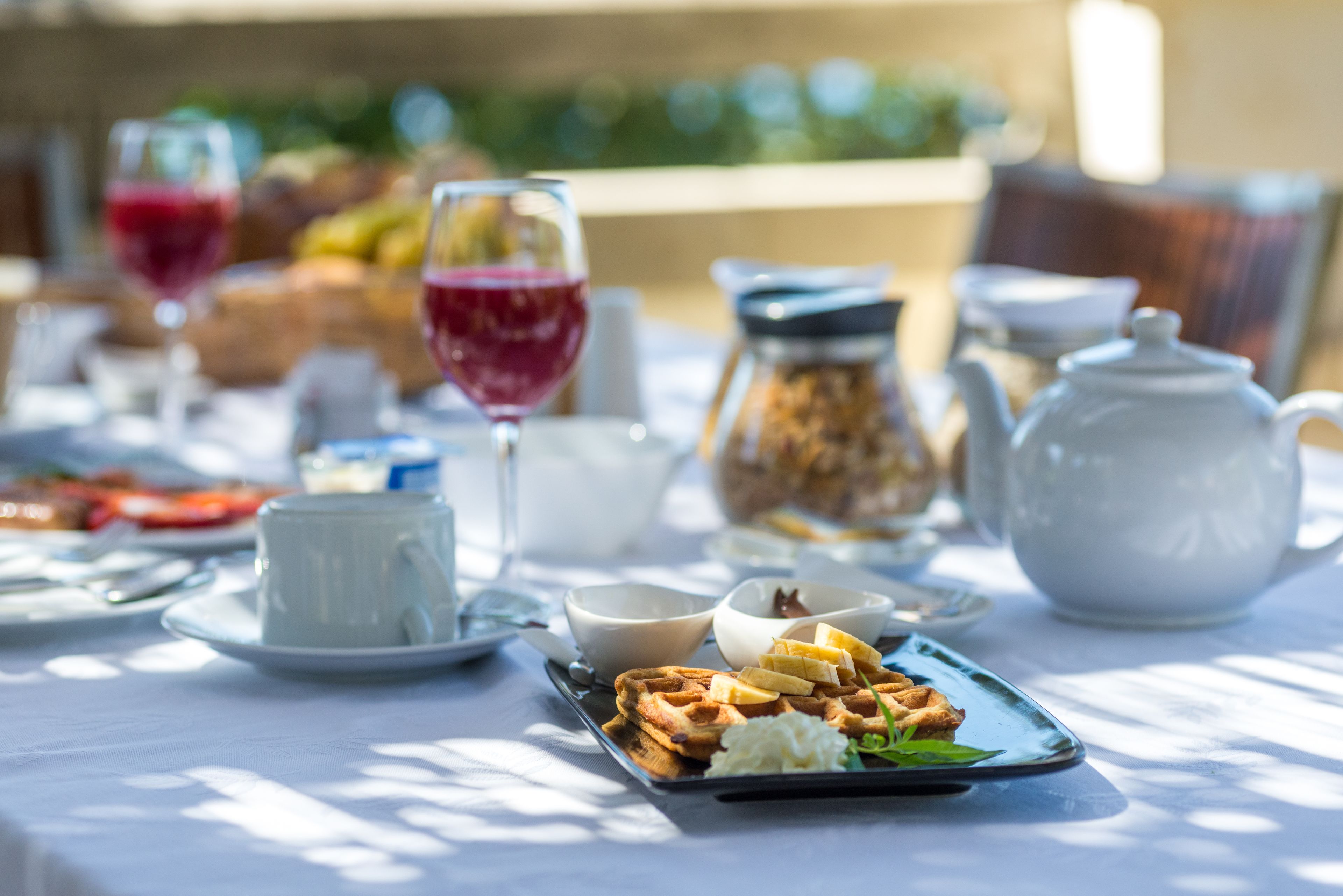 Una mesa dispuesta con gofres, una taza, un bol y una tetera.