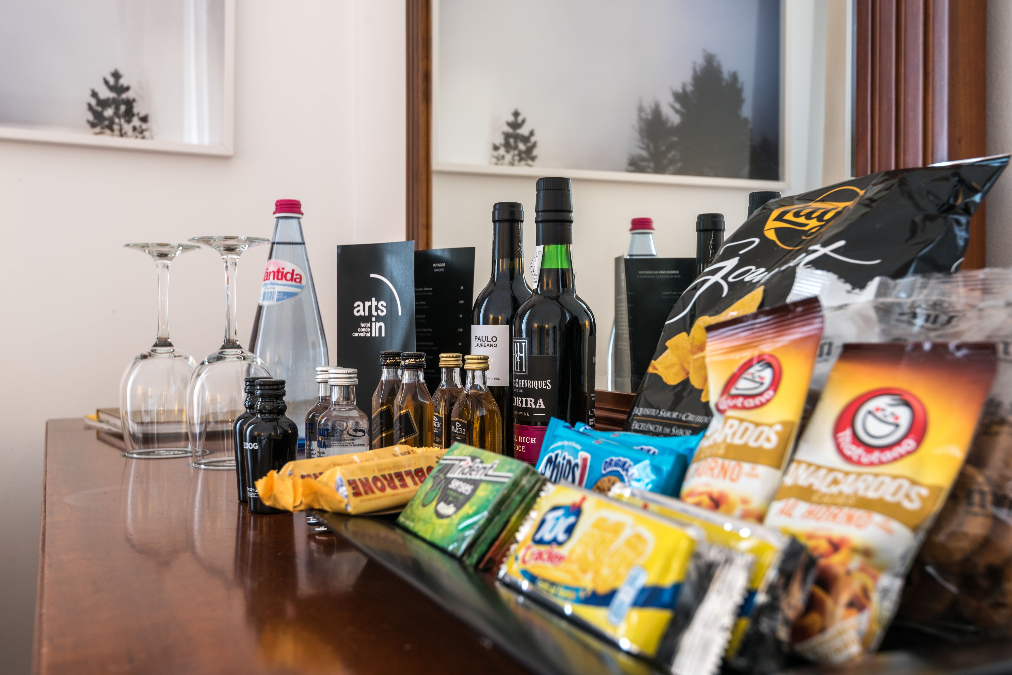 Uma área de bar com diversos tipos de bebidas, copos e petiscos.