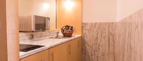 A modern kitchen with a marble countertop, wooden cabinets, and a built-in microwave.