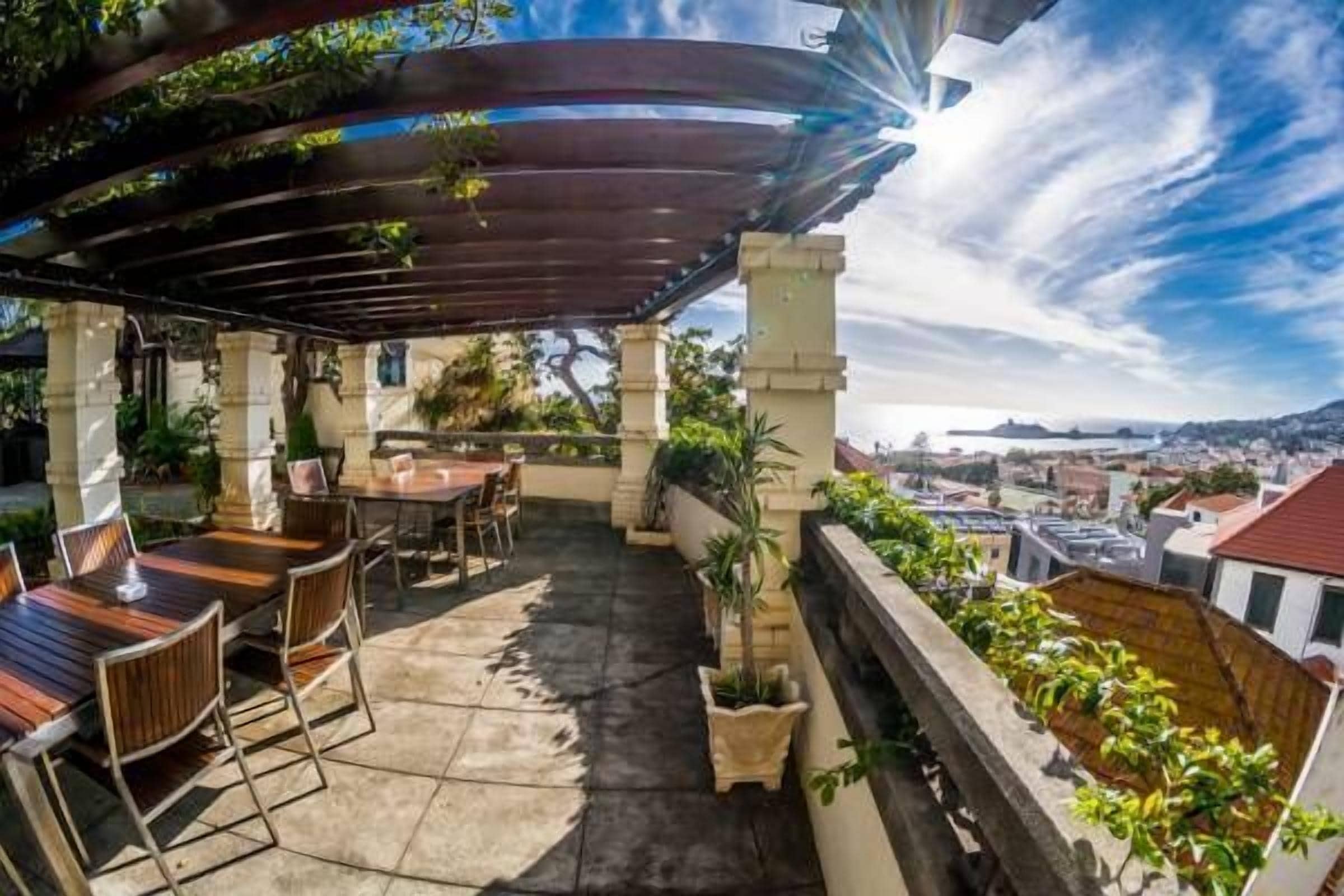 Eine Dachterrasse mit einer Pergola, Sitzgelegenheiten im Freien und Kübelpflanzen.