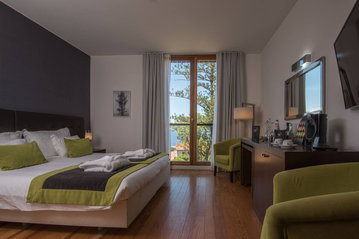 Habitación de hotel moderna con una cama grande, un escritorio y vistas al exterior.