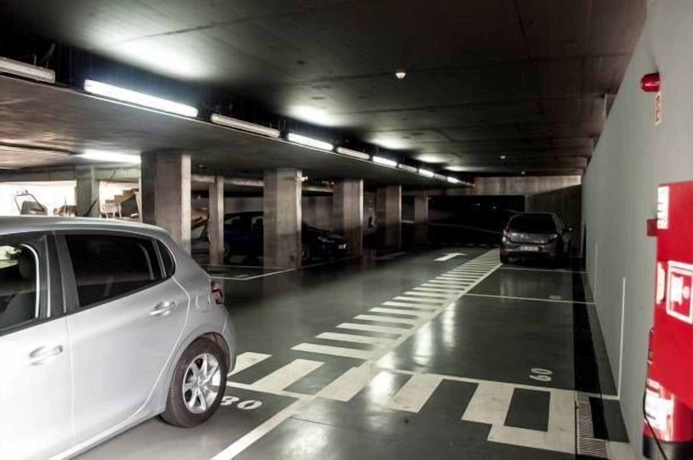 A multi-level parking garage with concrete pillars, marked parking spaces, and overhead lighting.