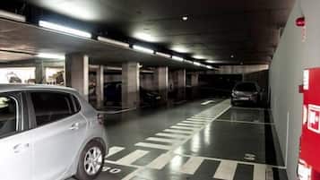 A multi-level parking garage with concrete pillars, marked parking spaces, and overhead lighting.