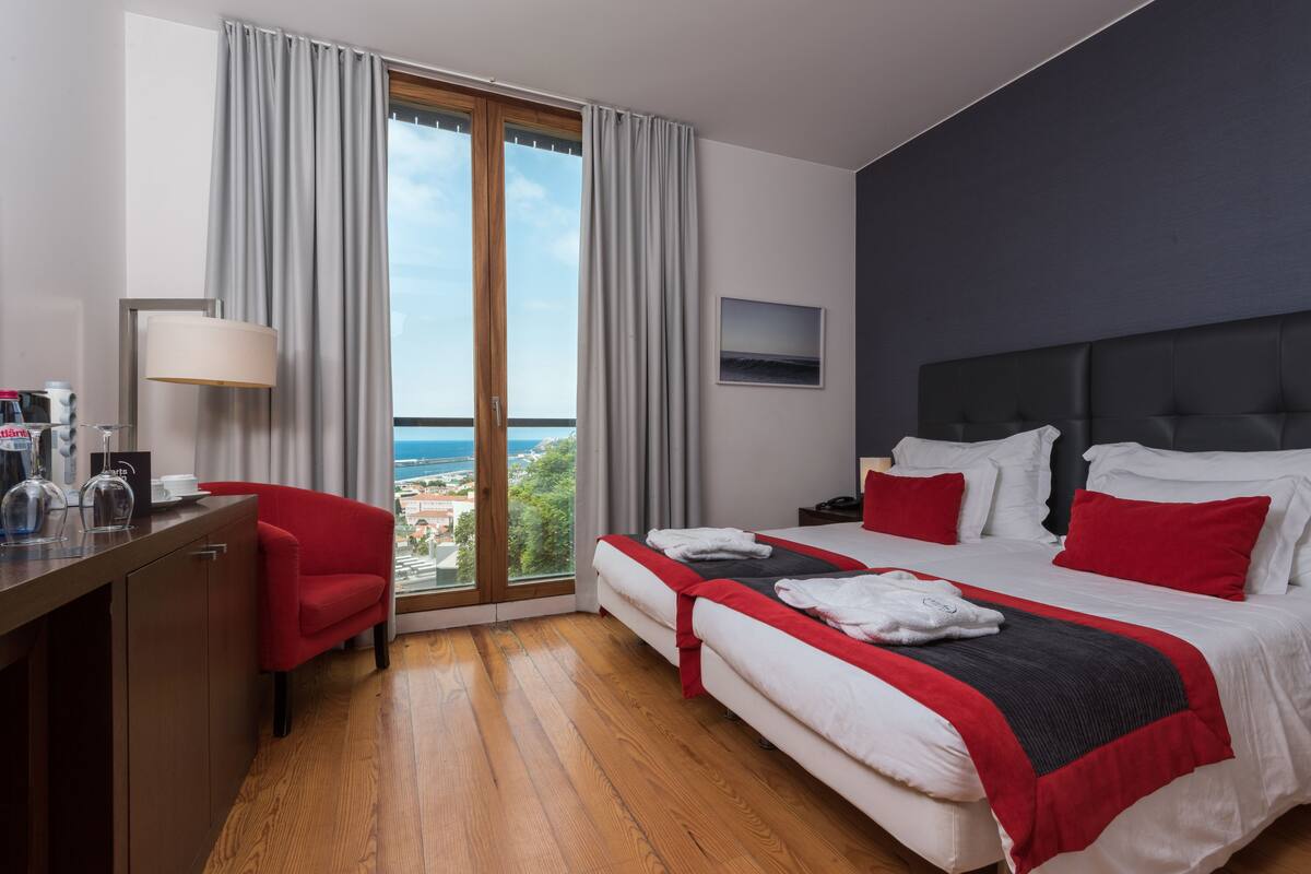 Habitación de hotel con cama, escritorio, silla y vista al mar.