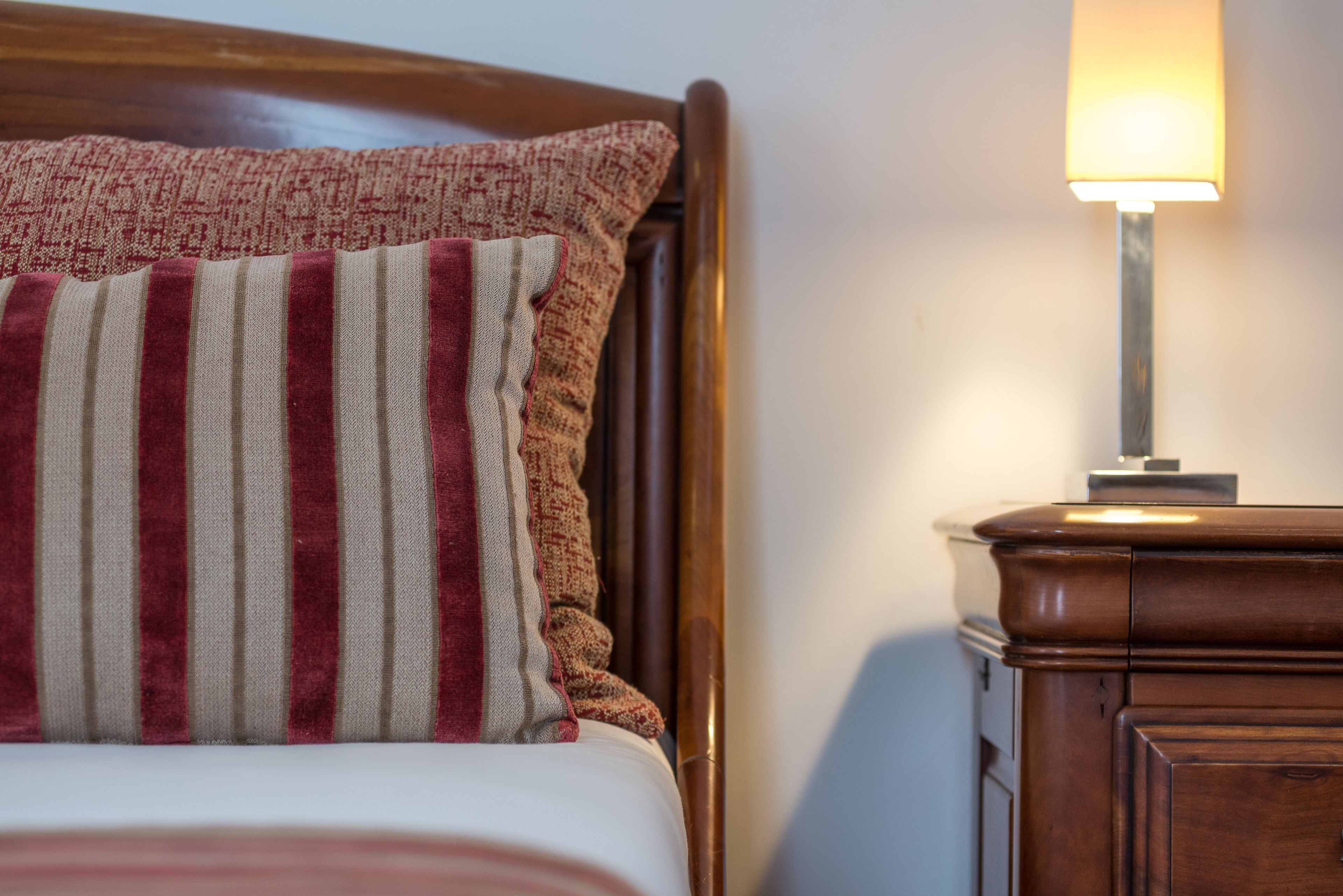 A bed with a striped pillow and a bedside table with a lamp.