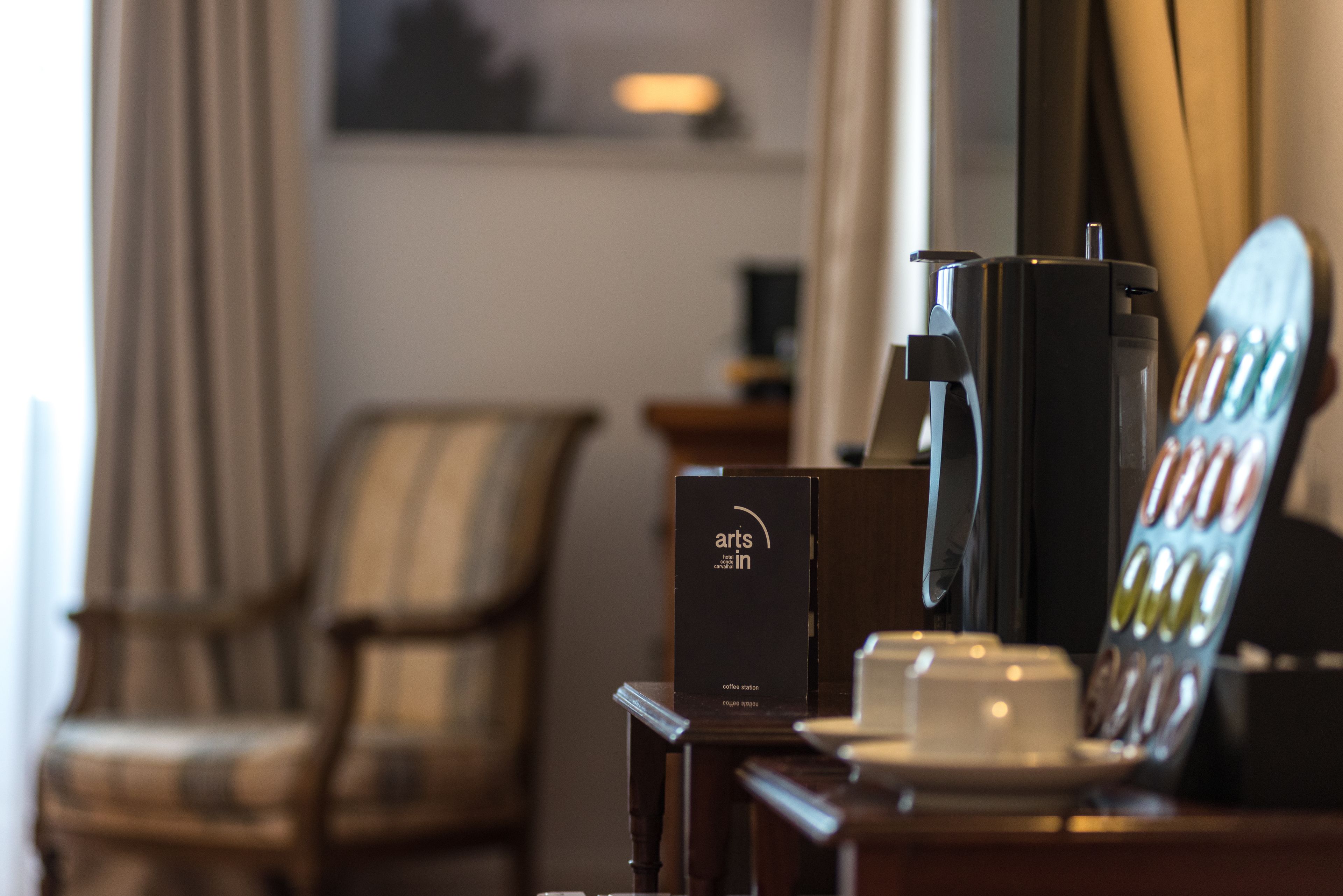 A coffee station with a coffee machine, a box labeled 'arts in', and a tray of coffee cups.