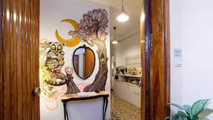 A reception area with a wooden desk, a mirror, and a wall mural. - Martini Bed (Rome)