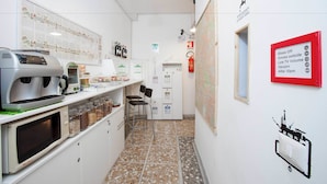 A narrow hallway with a coffee machine, seating area, and a fire extinguisher. - Martini Bed (Rome)
