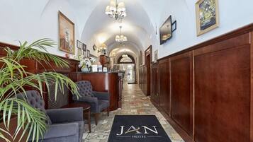 A hotel lobby with a reception desk, seating area, and a chandelier.