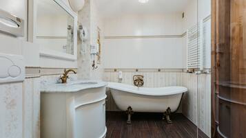 A bathroom with a freestanding bathtub, a vanity with a marble countertop, and a large mirror.