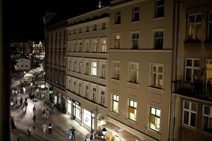 A nighttime view of a historic building with multiple floors, large windows, and a central open space with people walking.