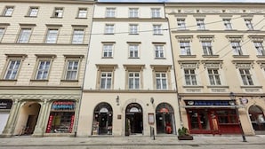 A row of three-story buildings with storefronts, including a pharmacy and a bar. - Hotel Jan (Kraków)
